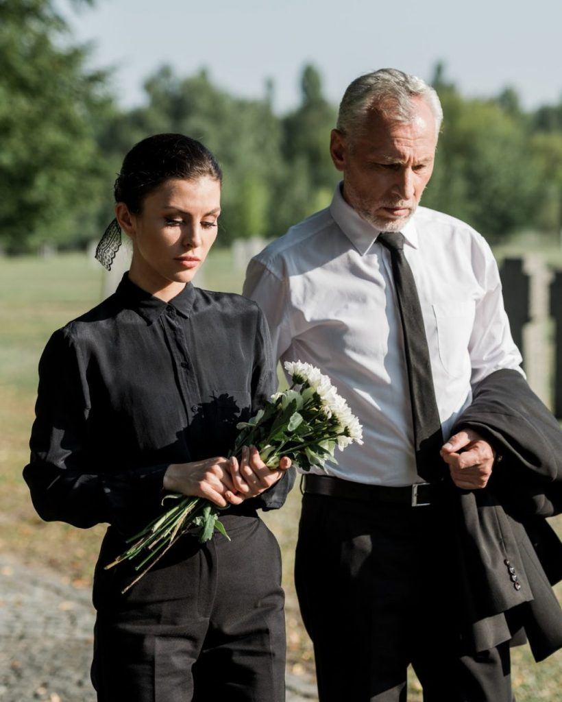 Angehörige mit Blumen auf dem Friedhof